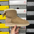 UGG Mini Bailey Bow Ankle Boot – Suede Boot with Cream Shearling Lining, Satin Bow Detail & Sand Sugar Sole in Sand